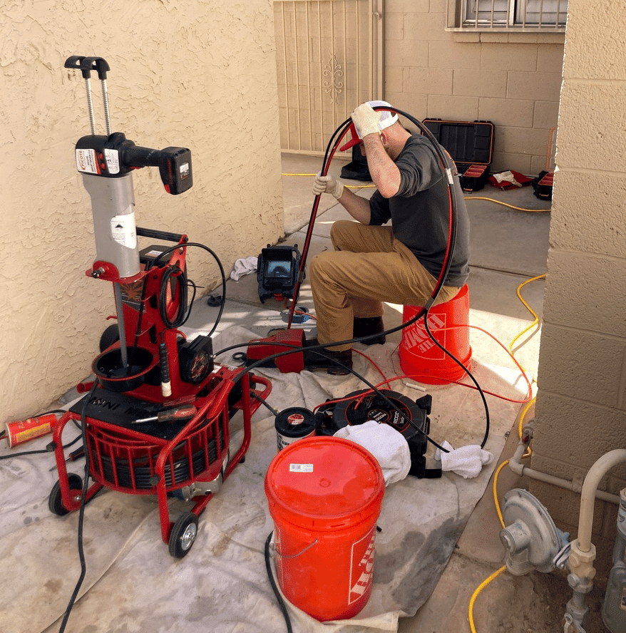 a person working in a home with red drain equipment